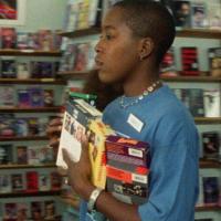 Grainy image of woman with arms full of VHS tapes